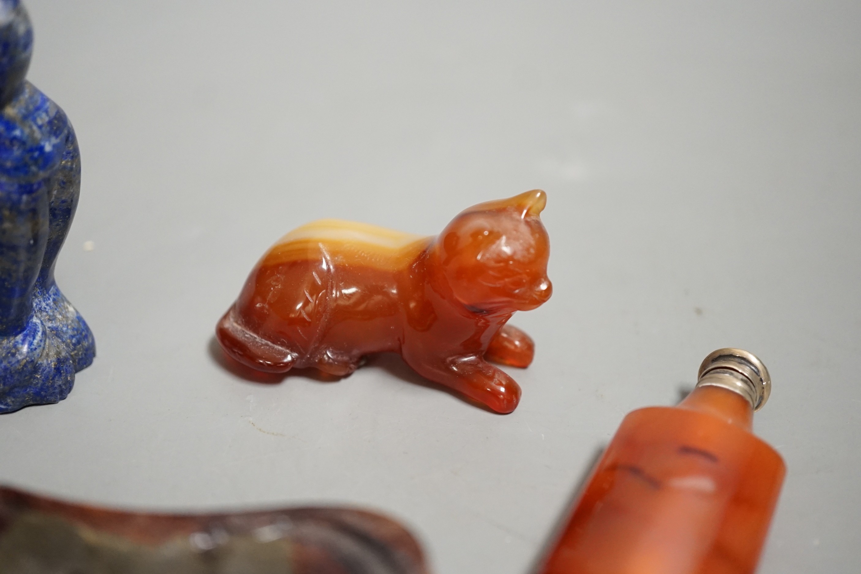 A Chinese carved lapis lazuli seated cat, a banded agate recumbent cat on hardwood stand and a white metal mounted agate scent bottle